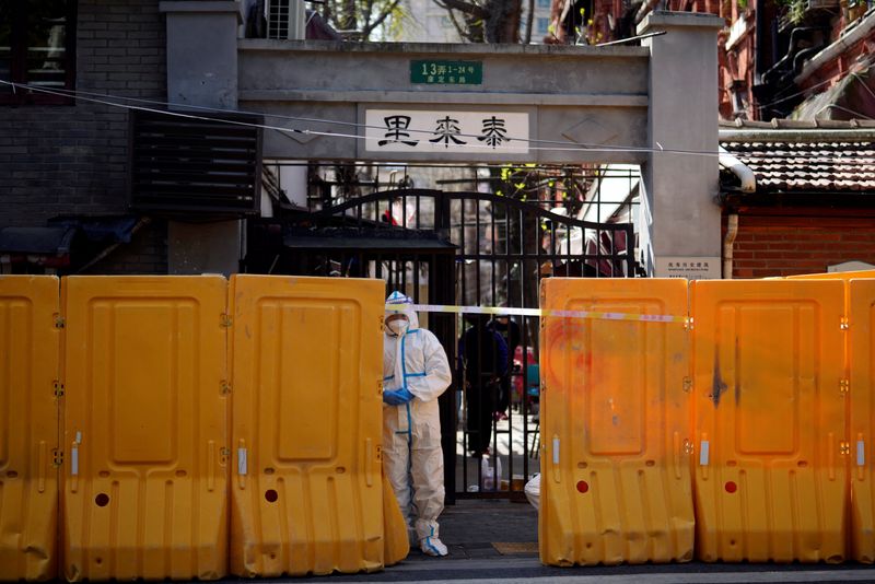 © Reuters. A worker in a protective suit stands behind barriers sealing off a residential area under lockdown, following the coronavirus disease (COVID-19) outbreak in Shanghai, China March 29, 2022. REUTERS/Aly Song