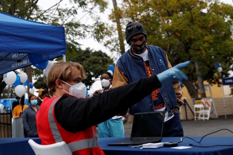&copy; Reuters. A health care worker points to a man wearing a protective face mask while waiting in line to receive one of the available first, second and booster doses of the coronavirus disease (COVID-19) vaccine at the L.A. Care Health Plan free testing and vaccinati