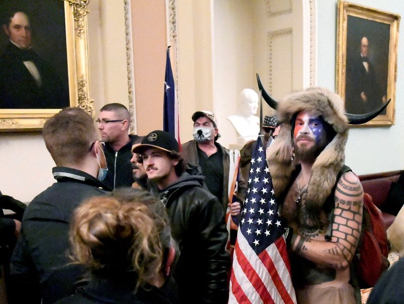 © Reuters. FILE PHOTO: Jacob Anthony Chansley, also known as Jake Angeli, of Arizona, stands with other supporters of U.S. President Donald Trump as they demonstrate on the second floor of the U.S. Capitol near the entrance to the Senate after breaching security defenses, in Washington, U.S., January 6, 2021. REUTERS/Mike Theiler/File Photo