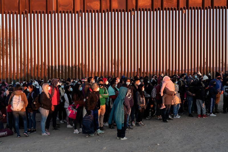 &copy; Reuters. FILE PHOTO: Migrants seeking asylum in the U.S., mostly from Venezuela, stand near the border fence while waiting to be processed by the U.S. border patrol after crossing the border from Mexico at Yuma, Arizona, U.S., January 23, 2022. REUTERS/Go Nakamura