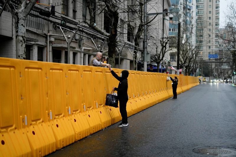 &copy; Reuters. FILE PHOTO: People pass food to residents over the barriers of an area under lockdown, amid the coronavirus disease (COVID-19) pandemic, in Shanghai, China March 25, 2022. REUTERS/Aly Song/File Photo