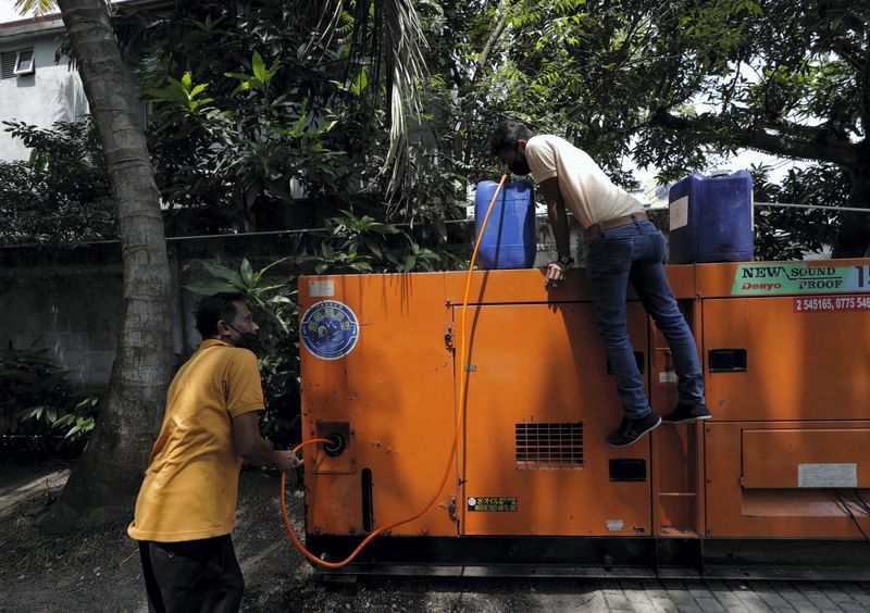 &copy; Reuters. FILE PHOTO: An employee of the Broadway Kids (Pvt) Ltd apparel factory checks the diesel can while refilling the generator during a seven hour power outage at the factory in a suburb of Colombo, Sri Lanka March 3, 2022. Picture taken March 3, 2022. REUTER