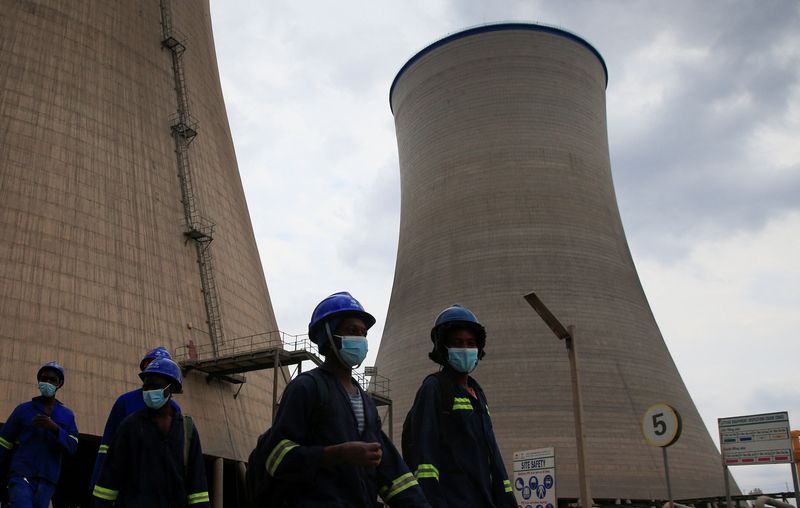 &copy; Reuters. Workers walk beneath cooling towers at Hwange Power station's Phase 8, currently under construction, in Hwange, Zimbabwe, October 19, 2021. REUTERS/Philimon Bulawayo