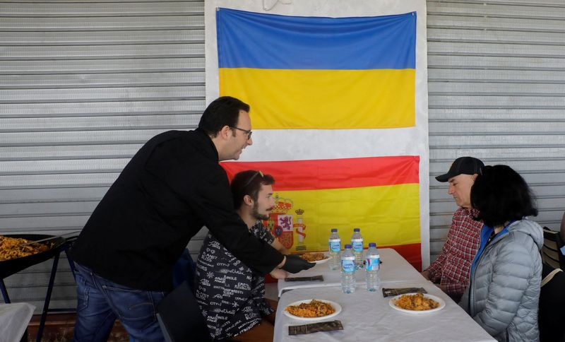 &copy; Reuters. El chef español Ciriaco Vicente, de 47 años, sirve una paella en su restaurante de la playa, cerca de Valencia, a los refugiados ucranianos Bohdan Turinulka, de 24 años, y su madre Yulia, de 49 años, junto con Ramón Padilla, de 61 años, un español 