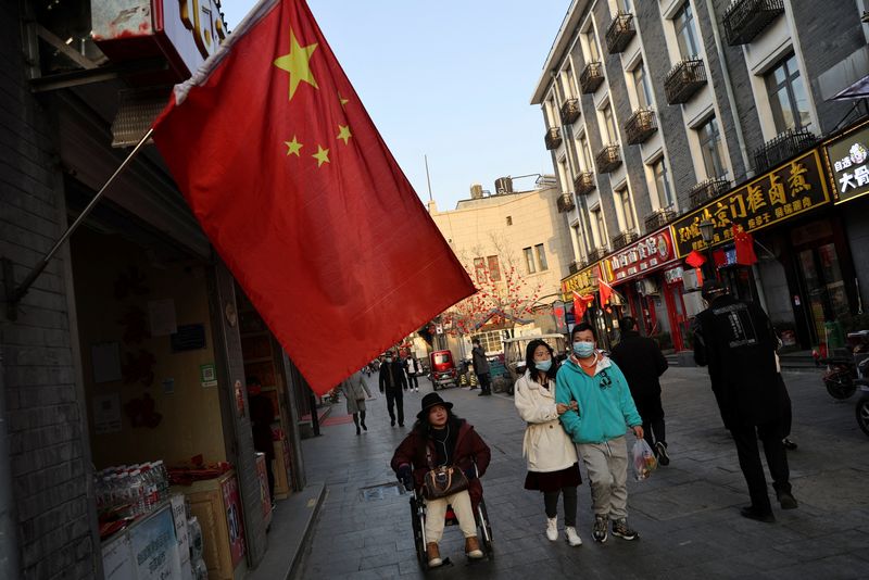 &copy; Reuters. Pedestres caminham em frente a bandeira da China, em Pequim
03/03/2022
REUTERS/Tingshu Wang