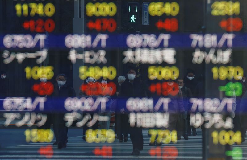&copy; Reuters. Pedestrians wearing protective masks, amid the coronavirus disease (COVID-19) outbreak, are reflected on an electronic board displaying various company’s stock prices outside a brokerage in Tokyo, Japan, February 25, 2022. REUTERS/Kim Kyung-Hoon
