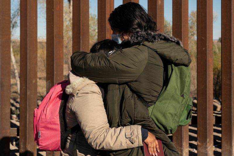 © Reuters. FILE PHOTO: Migrants seeking asylum in the U.S. from Colombia embrace each other while waiting to be transported by the U.S. border patrol after crossing the border from Mexico at Yuma, Arizona, U.S., February 18, 2022. REUTERS/Go Nakamura/File Photo