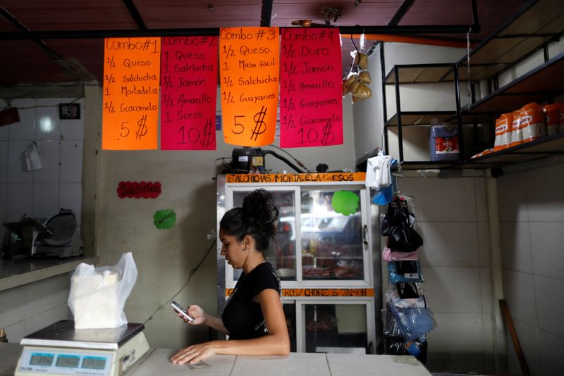 &copy; Reuters. FILE PHOTO: A worker checks her phone in a store that sells sausages in a market in Caracas, Venezuela, August 12, 2021. REUTERS/Leonardo Fernandez Viloria