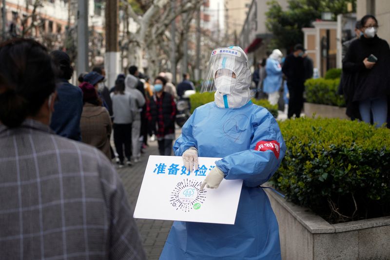 &copy; Reuters. A worker in a protective suit shows a QR code to residents lining up for nucleic acid testing, as the second stage of a two-stage lockdown to curb the spread of the coronavirus disease (COVID-19) begins in Shanghai, China April 1, 2022. REUTERS/Aly Song