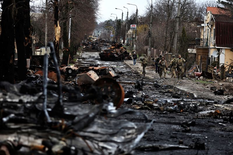 © Reuters. جنود يمرون بجوار مركبة روسية مصفحة دمرت في المعارك في بوتشا في منطقة كييف عاصمة أوكرانيا يوم السبت. تصوير: زهرة بن سمرة - رويترز. 