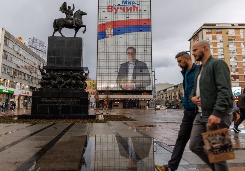 &copy; Reuters. شخصان يمران بملصق دعائي انتخابي لألكسندر فوتشيتش في نيس في الأول من أبريل نيسان 2022. تصوير: أنطونيو برونيتش - رويترز