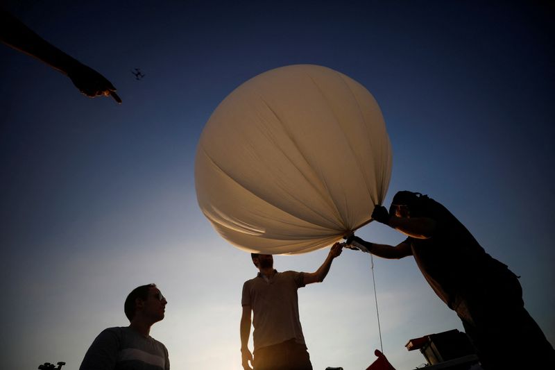 &copy; Reuters. FILE PHOTO: People hold a balloon during a demonstration by Israeli startup High Hopes Labs who are developing a balloon that captures carbon directly from the atmosphere at a high altitude, in Petah Tikva, Israel November 3, 2021. REUTERS/Amir Cohen/File