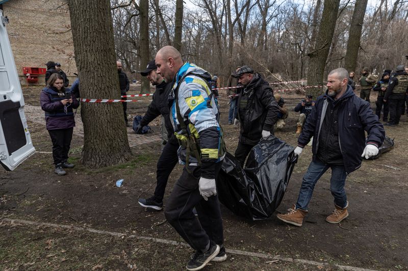 © Reuters. أفراد من القوات الأوكرانية يحملون جثة تم العثور عليها في قبو ببلدة بوتشا على مشارف كييف يوم الاثنين. تصوير: ماركو ديوريتشا-رويترز.