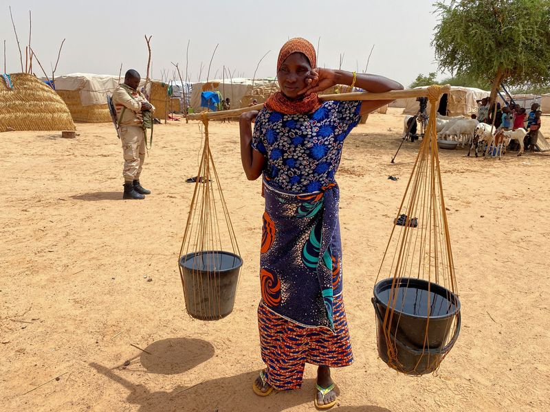 © Reuters. امرأة تحمل المياه في معسكر للنازحين في بلدة أوالام بالنيجر يوم 6 يوليو تموز 2021. تصوير:رويترز.