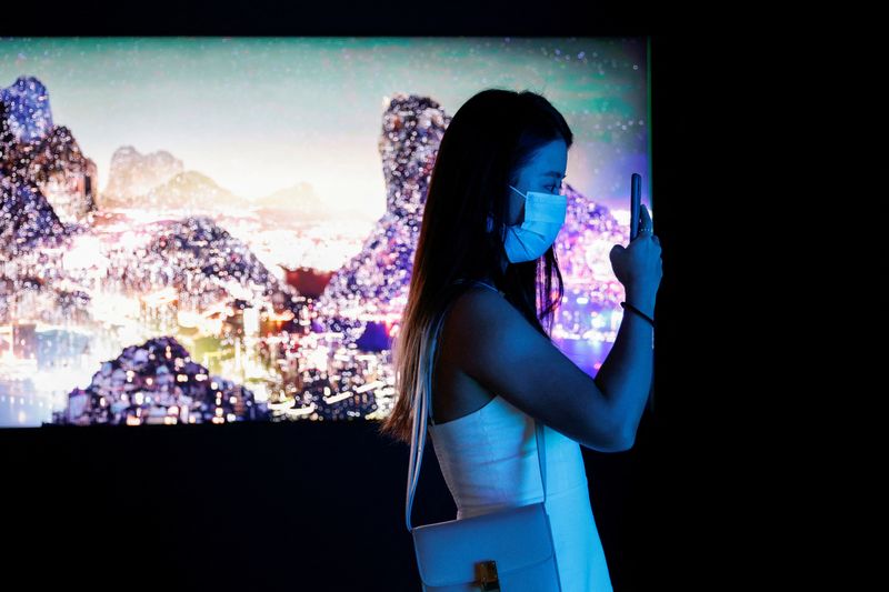 &copy; Reuters. FILE PHOTO: A visitor takes a photo in front of a video installation "Glows in the Night" by Chinese contemporary artist Yang Yongliang, which will be converted into NFTs and auctioned online at Sotheby's, at the Digital Art Fair, in Hong Kong, China Sept