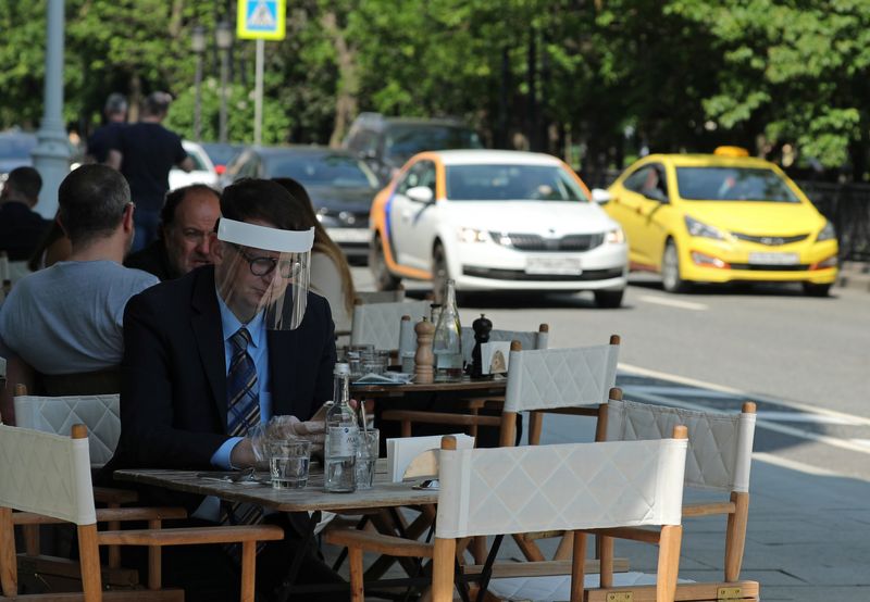 &copy; Reuters. FILE PHOTO: A man wearing a protective face shield sits in a cafe as restaurants and cafes reopen summer terraces following the easing of measures against the spread of the?coronavirus?disease (COVID-19), in Moscow, Russia June 16, 2020. REUTERS/Evgenia N