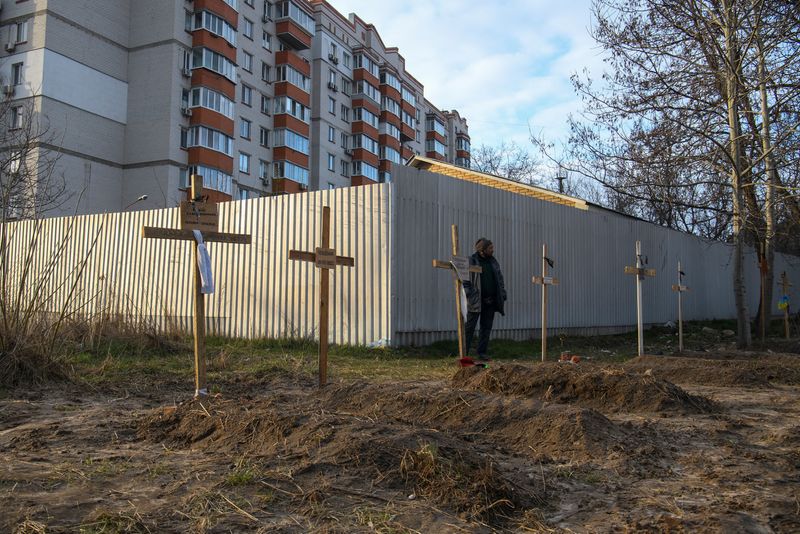 &copy; Reuters. Un hombre en pie junto a las tumbas de varios civiles que, según los residentes locales, fueron asesinados por soldados rusos en Bucha, óblast de Kiev, Ucrania, el 4 de abril de 2022. REUTERS/Vladyslav Musiienko