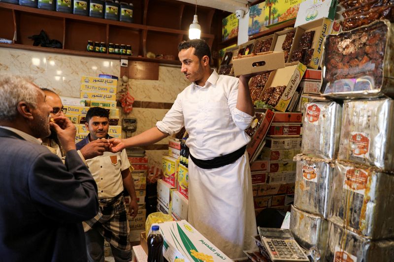 &copy; Reuters. FOTO DE ARCHIVO: Un hombre reparte dátiles entre varios clientes de cara a la preparación para el mes de Ramadán en una tienda de Saná, Yemen, el 1 de abril de 2022. REUTERS/Khaled Abdullah
