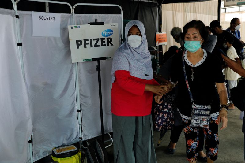 &copy; Reuters. FILE PHOTO: A woman helps an elderly woman who just received a booster dose of Pfizer vaccine, as the country starts the booster vaccination program for the general public amid the rise of the Omicron variant in Jakarta, Indonesia, January 12, 2022. REUTE