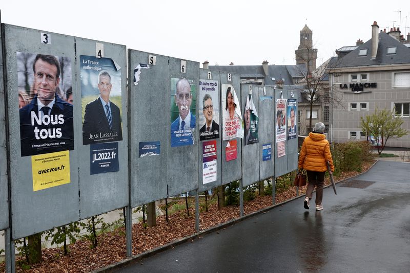 &copy; Reuters. Una mujer pasa junto a un muro lleno de carteles electorales en Vire, Francia. 5 abril 2022. REUTERS/Noemie Olive