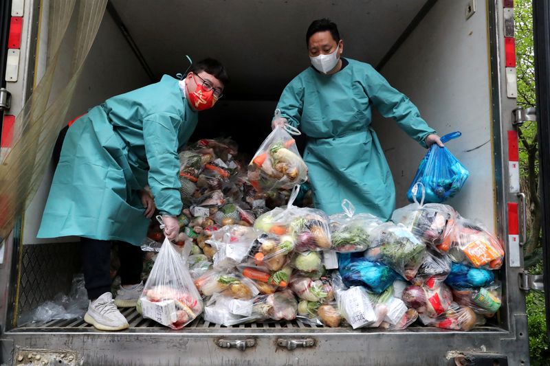 &copy; Reuters. FILE PHOTO: Workers wearing protective gear sort bags of vegetables and groceries on a truck to distribute them to residents at a residential compound, during the lockdown to curb the coronavirus disease (COVID-19) outbreak in Shanghai, China April 5, 202