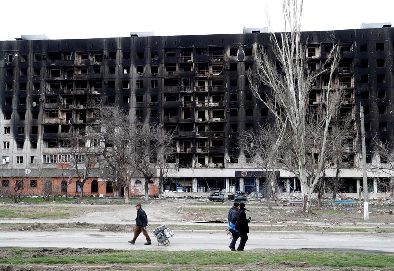 &copy; Reuters. شخصان من السكان المحليين يمران بمبنى احترق خلال الصراع الأوكراني-الروسي في ماريوبول في الرابع من أبريل نيسان 2022. تصوير: ألكسندر إيرموتشينكو