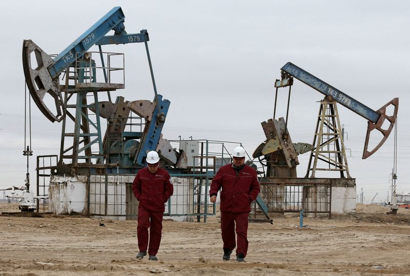 © Reuters. FILE PHOTO: Workers walk as oil pumps are seen in the background in the Uzen oil and gas field in the Mangistau Region of Kazakhstan November 13, 2021. REUTERS/Pavel Mikheyev
