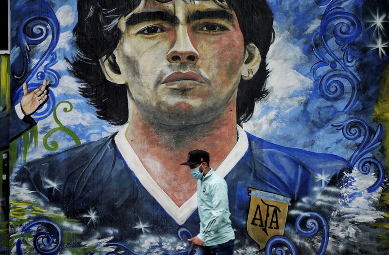 &copy; Reuters. FOTO DE ARCHIVO: Una persona pasa frente a un mural de la leyenda del fútbol Diego Armando Maradona en La Boca en el primer aniversario de su muerte en Buenos Aires, Argentina, 25 de noviembre del  2021. REUTERS/Mariana Nedelcu 