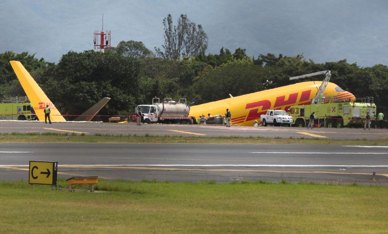 © Reuters. Firefighters work at the scene where a Boeing 757-200 cargo aircraft operated by DHL made an emergency landing before skidding off the runway and splitting, aviation authorities said, at the Juan Santamaria International Airport in Alajuela, Costa Rica April 7, 2022. REUTERS/Mayela Lopez
