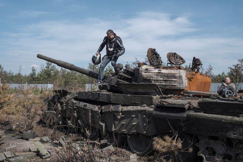 © Reuters. رجل يعتلي دبابة روسية دمرت في الغزو الروسي لأوكرانيا في منطقة كييف يوم الخميس. تصوير: ماركو ديوريتسا - رويترز
