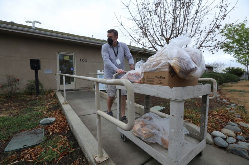 &copy; Reuters. Paul Wolfe, donations and volunteer coordinator at the Torres Community Shelter, pulls a cart carrying plastic bags full of bread donated by Panera Bread in Chico, California, U.S. March 15, 2022. REUTERS/Nathan Frandino