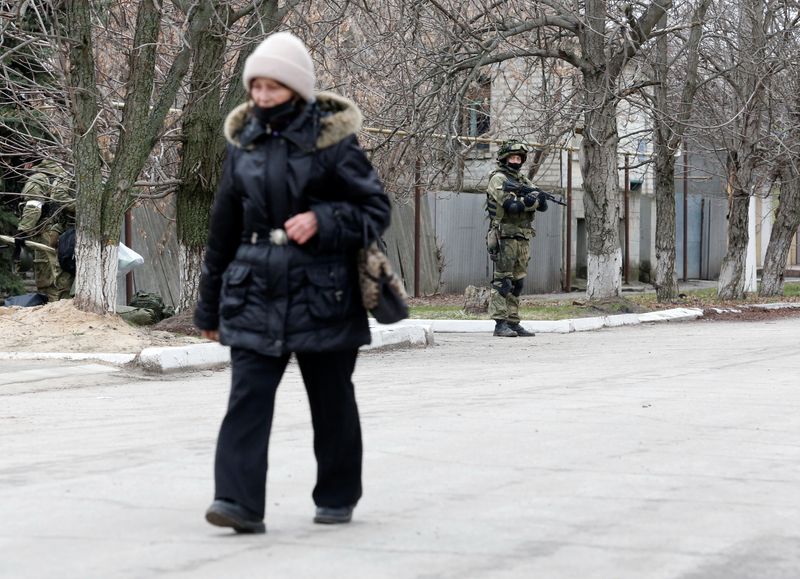 &copy; Reuters. Foto de archivo de una mujer caminando cerca de un militar prorruso en Stanytsia
Feb 27, 2022. REUTERS/Alexander Ermochenko