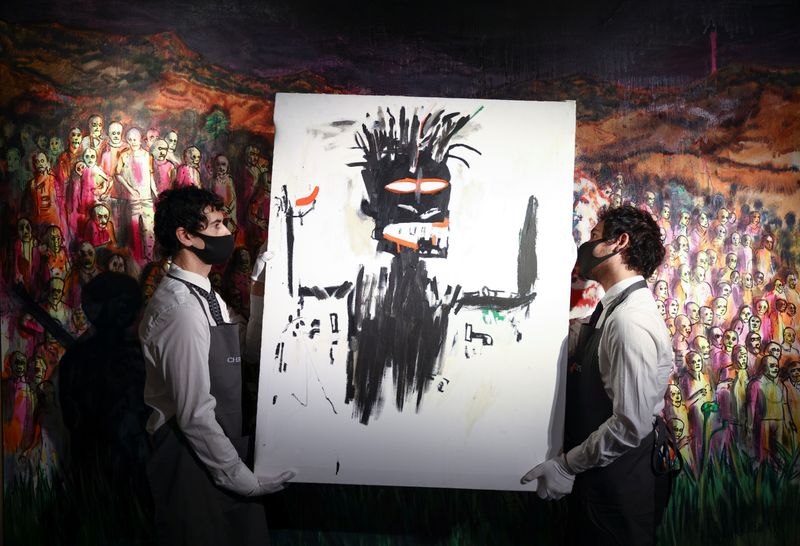 &copy; Reuters. FOTO DE ARCHIVO-Asistentes de la galería sostienen una obra de arte titulada "Autorretrato" de Jean-Michel Basquiat en la casa de subastas Christie's, en Londres, Gran Bretaña. 16 de marzo de 2021. REUTERS/Henry Nicholls