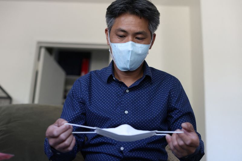 © Reuters. FILE PHOTO: LA-based freight forwarder Tony Chen checks a kid-sized KF94 mask made in South Korea in his living room in South Pasadena, California, U.S., January 27, 2022. Picture taken January 27, 2022. REUTERS/Mario Anzuoni