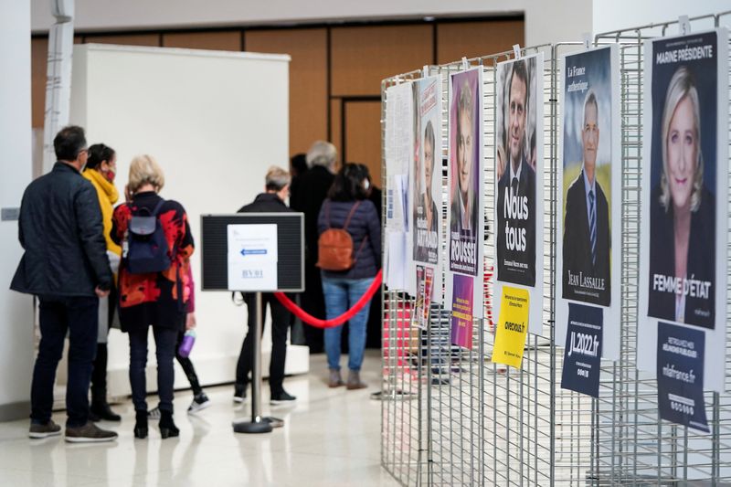 &copy; Reuters. مواطنون فرنسيون يصطفون بالقرب من ملصقات انتخابية لدى وصولهم للإدلاء بأصواتهم في الجولة الأولى من الانتخابات الرئاسية الفرنسية في السفارة 