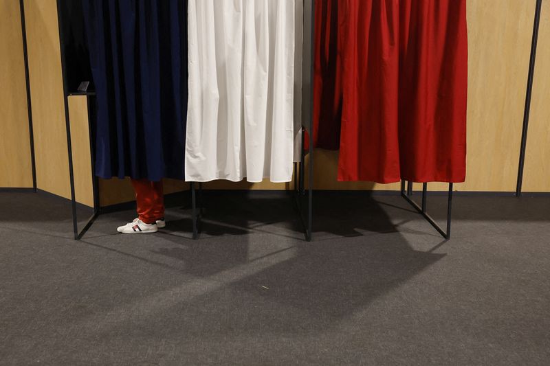 © Reuters. ناخب يدلي بصوته خلف حاجز يعمل ألوان علم فرنسا في مركز اقتراع في لو توكيه باريس بلاد بفرنسا يوم الأحد. تصوير:كريستيان هارتمان-رويترز.