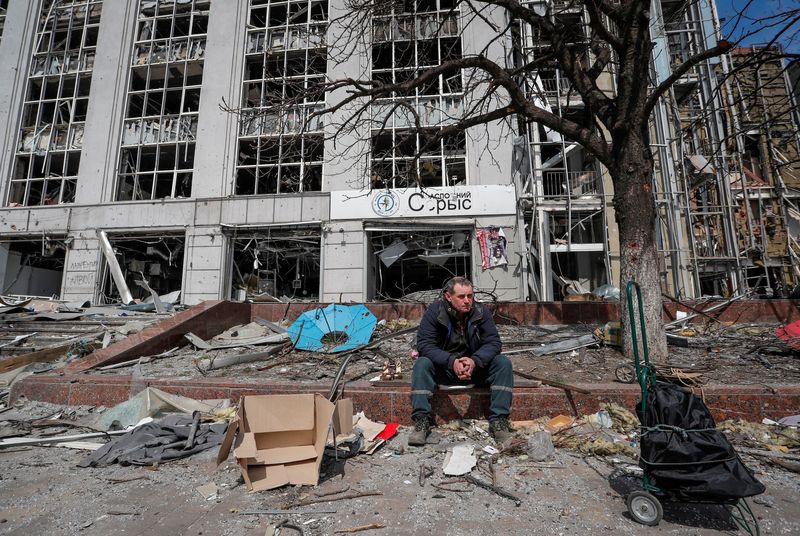 &copy; Reuters. شخص يجلس أمام مبنى دُمر خلال الصراع الروسي الأوكراني في ماريوبول يوم الأحد. تصوير: ألكسندر إيرموتشينكو - رويترز