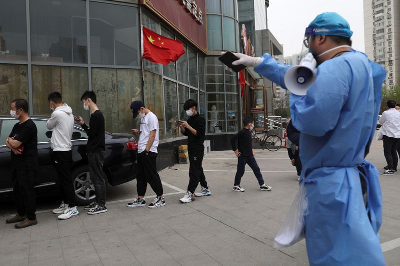 &copy; Reuters. FOTO DE ARCHIVO: Un trabajador guía a las personas mientras hacen cola para realizar una prueba de ácido nucleico en un centro de pruebas móvil tras el brote de la enfermedad por coronavirus (COVID-19), en Pekín, China, 11 de abril de 2022. REUTERS/Ti