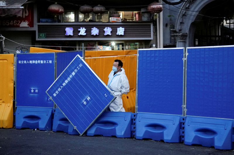 &copy; Reuters. A worker in a protective suit keeps watch next to barricades set around a sealed-off area, during a lockdown to curb the spread of the coronavirus disease (COVID-19) in Shanghai, China April 11, 2022. REUTERS/Aly Song 
