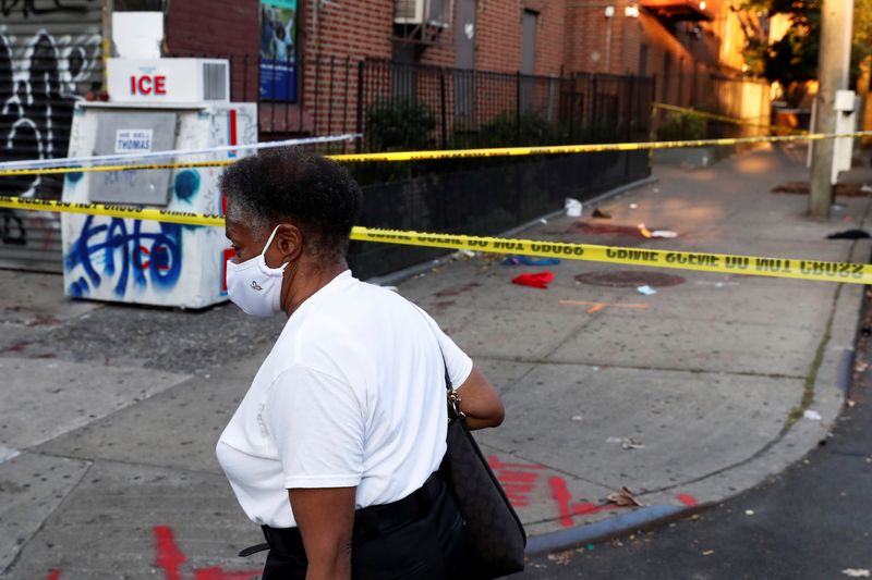 &copy; Reuters. FILE PHOTO: A woman wearing a protective face mask walks by NYPD crime scene police tape, where according to local media reports five people were shot, including a 6-year-old boy, early Monday during an outdoor J’Ouvert celebration, in the Crown Heights