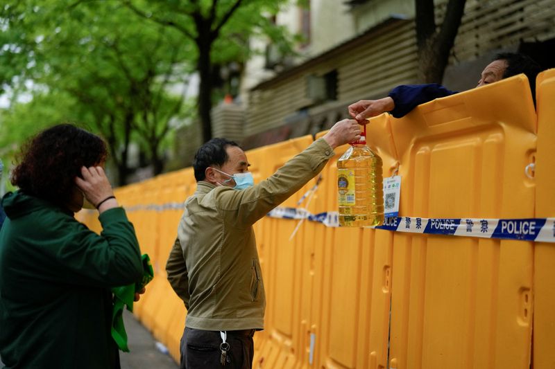 &copy; Reuters. La gente pasa aceite para cocinar por encima de las barreras en un mercado callejero confinado en medio de la pandemia de la enfermedad del coronavirus (COVID-19), en Shanghái, China el 13 de abril de 2022. REUTERS/Aly Song