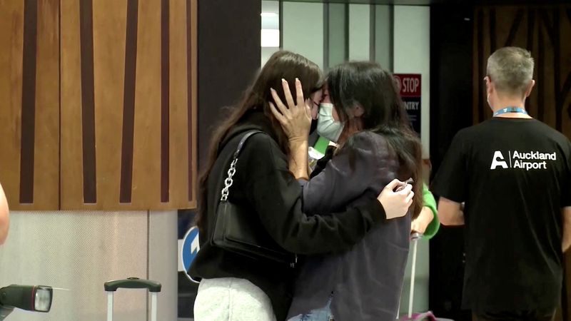 © Reuters. People hug in the arrivals area at the Auckland Airport, as Australians started arriving after the country opened its borders to travellers from its neighbouring nation for the first time since mid-2021, in Auckland, New Zealand, April 13, 2022 in this still image taken from a video. TVNZ/Handout via REUTERS