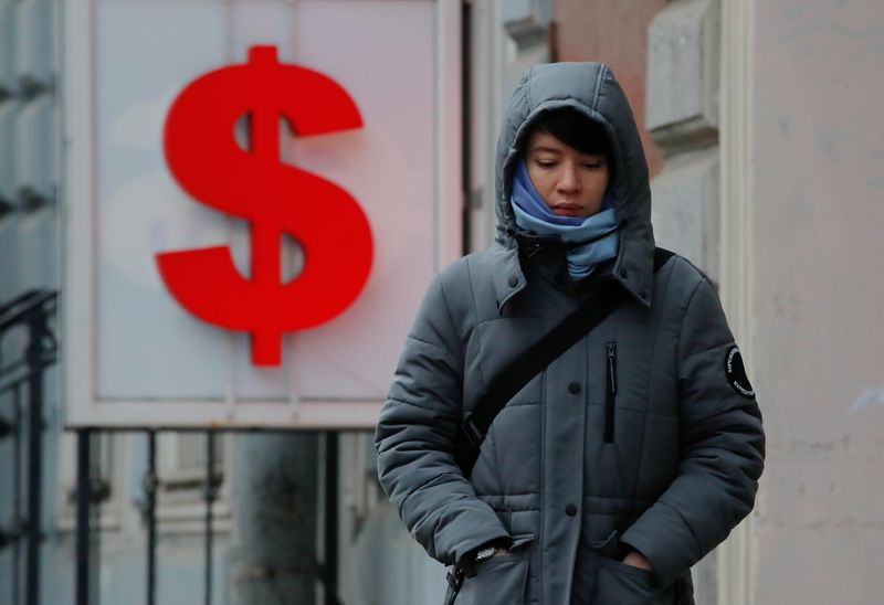 &copy; Reuters. FILE PHOTO: A woman walks past a board showing the U.S. dollar sign in a street in Saint Petersburg, Russia February 28, 2022. REUTERS/Anton Vaganov/File Photo