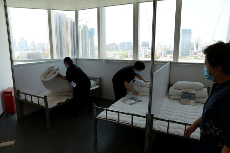 &copy; Reuters. FOTO DE ARCHIVO: Varias trabajadoras preparan camas en un edificio de oficinas para convertirlo en un hospital improvisado para paciendes con COVID-19 en Shanghái, China, el 12 de abril de 2022. China Daily via REUTERS