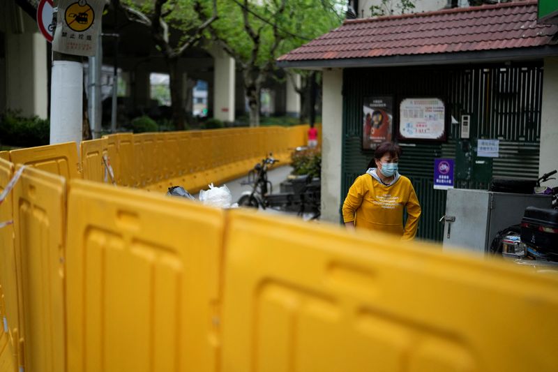 &copy; Reuters. Una mujer con mascarilla tras una barrera que rodea un área residencial durante la cuarentena por COVID-19 en Shanghái, Chinal el 14 de abril de 2022. REUTERS/Aly Song