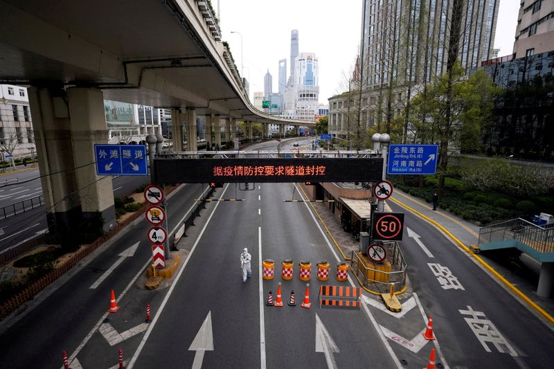 &copy; Reuters. FILE PHOTO: A worker in a protective suit walks at an entrance to a tunnel leading to the Pudong area, after restrictions on highway traffic amid the lockdown to contain the spread of the coronavirus disease (COVID-19) in Shanghai, China March 28, 2022. R