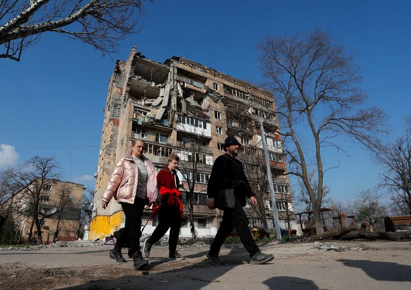 &copy; Reuters. سكان محليون يمرون أمام مبنى سكني لحق به الدمار في مدينة ماريوبول الساحلية جراء الصراع الروسي الأوكراني يوم 15 من أبريل نيسان 2022. تصوير: ألكسا
