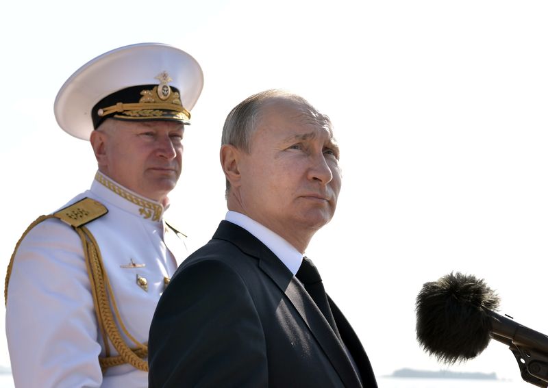&copy; Reuters. قائد البحرية الروسية الأميرال نيكولاي يفمينوف يقف خلف الرئيس فلاديمير بوتين أثناء مراسم في عيد البحرية في مدينة سان بطرسبرج في روسيا. صورة 