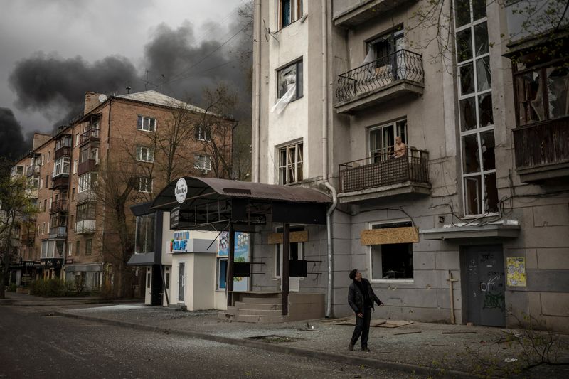 © Reuters. رجل يقف خارج مبنى سكني مدمر في خاركيف الروسية مع تصاعد أعمدة الدخان بعد قصف روسي يوم الأحد. تصوير: ألكيس قنسطنطنيدس - رويترز
