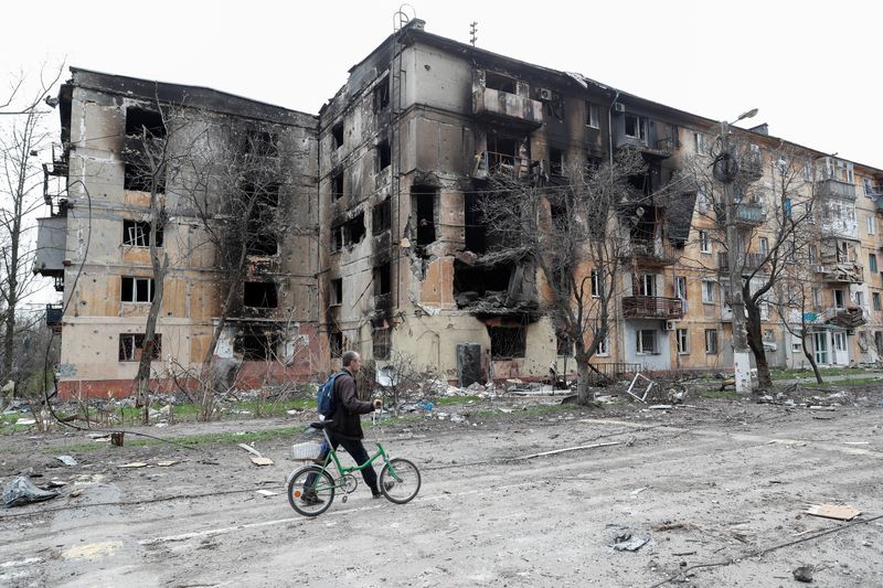 &copy; Reuters. رجل يسير بجوار مبنى تعرض لدمار بالغ في ماريوبول بأوكرانيا يوم الاثنين. تصوير: الكسندر ارموتشينكو - رويترز. 